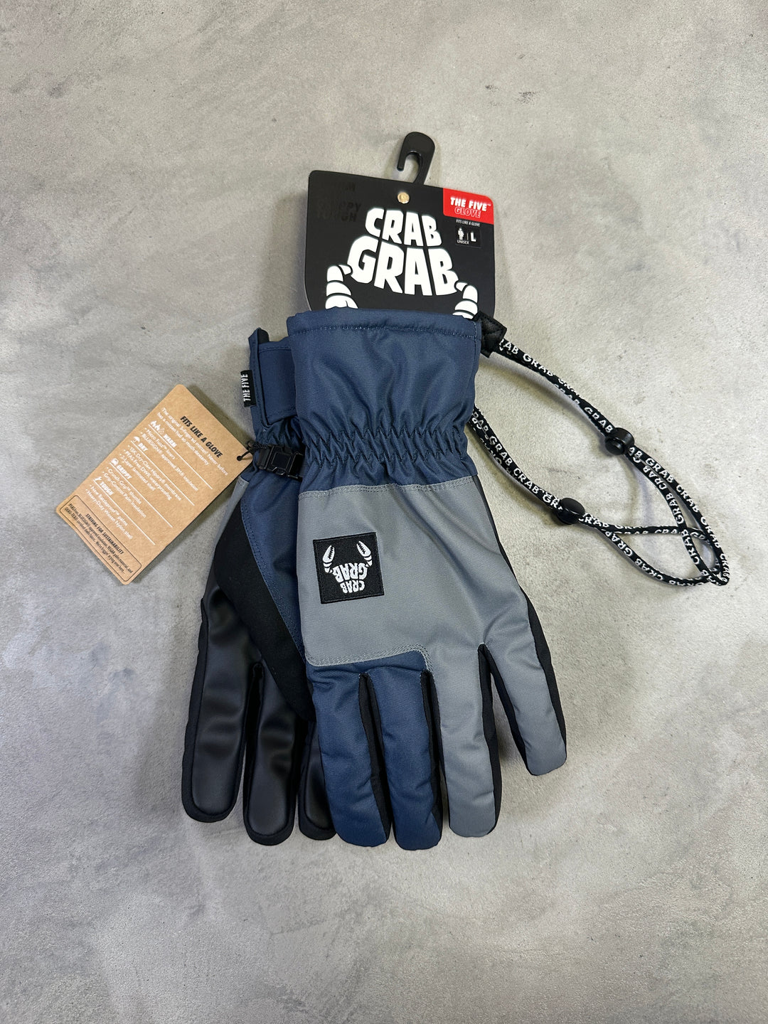 Pair of blue and gray gloves with tags on a gray surface