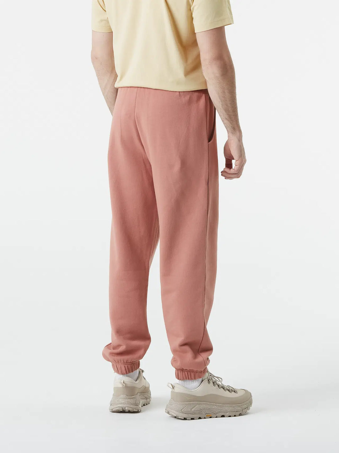 Person wearing pink sweatpants and a yellow shirt on a white background