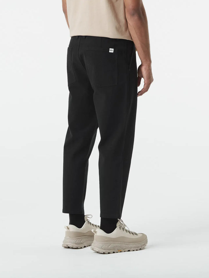 Person wearing black pants and white sneakers on a white background