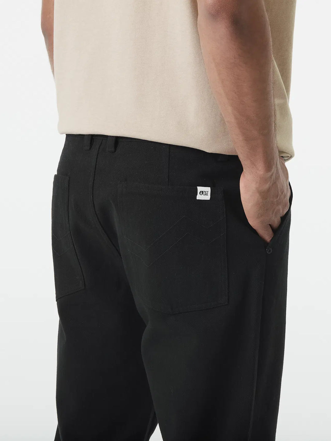 Person wearing black pants with a visible brand logo on a white background