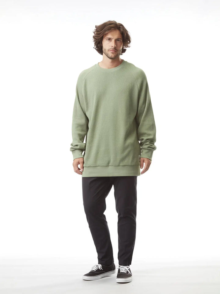 Man wearing a green sweatshirt and black pants on a white background