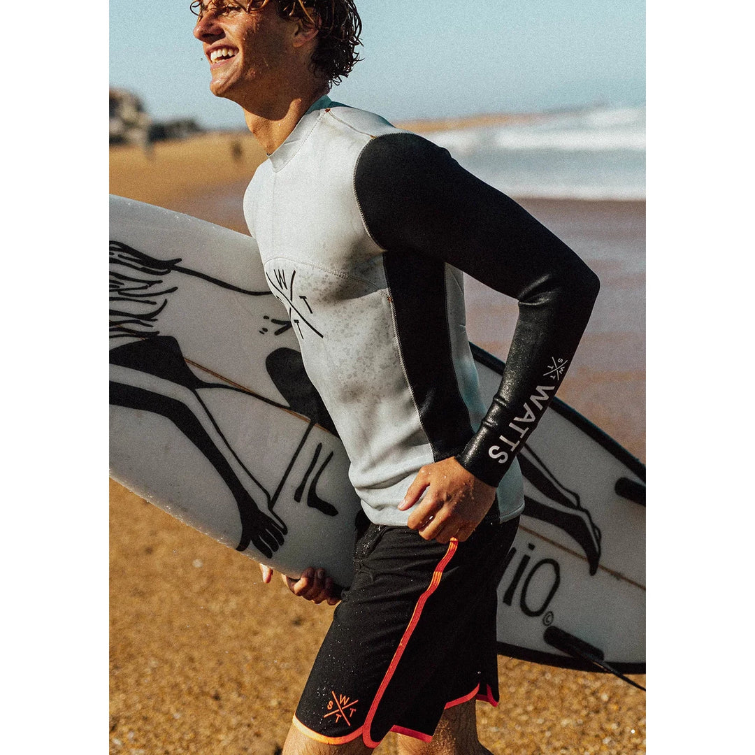 Person holding a surfboard on a beach with a clear sky