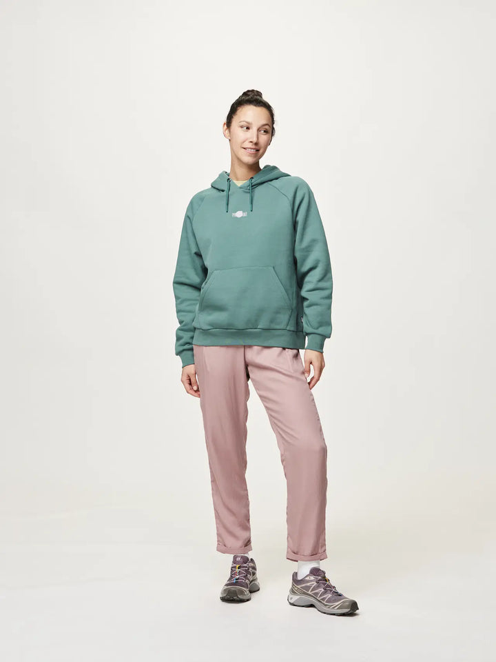 Person wearing a teal hoodie and pink pants on a white background