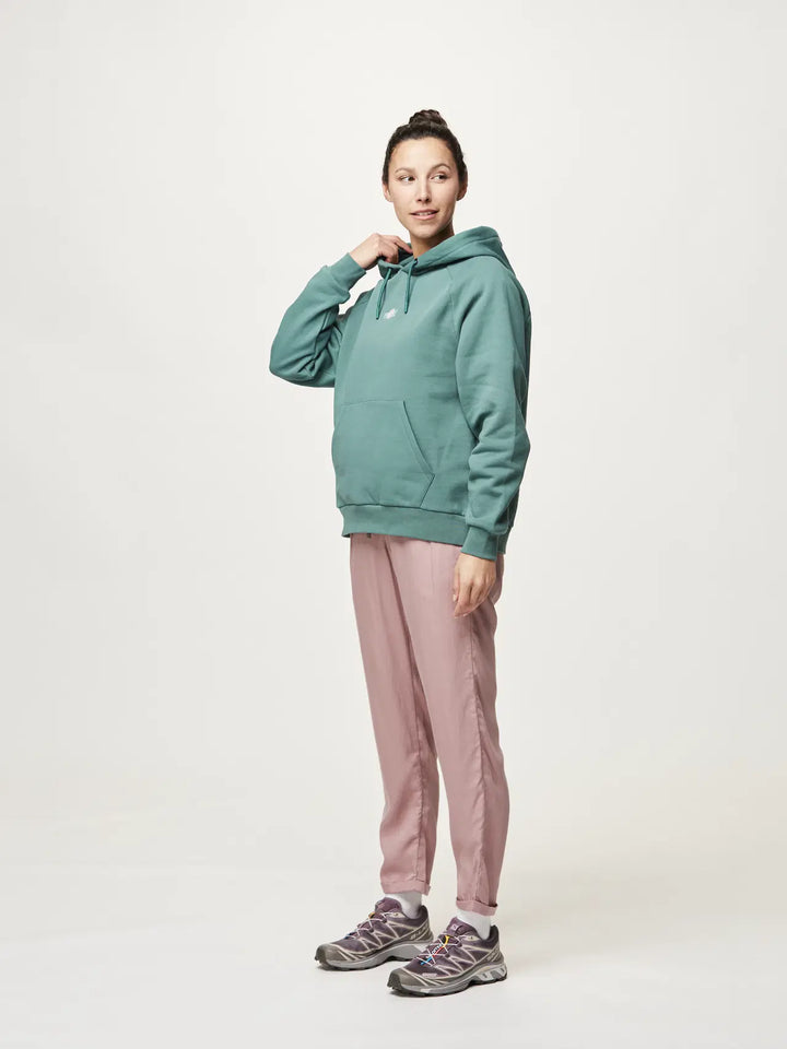 Person wearing a teal hoodie and pink pants on a white background