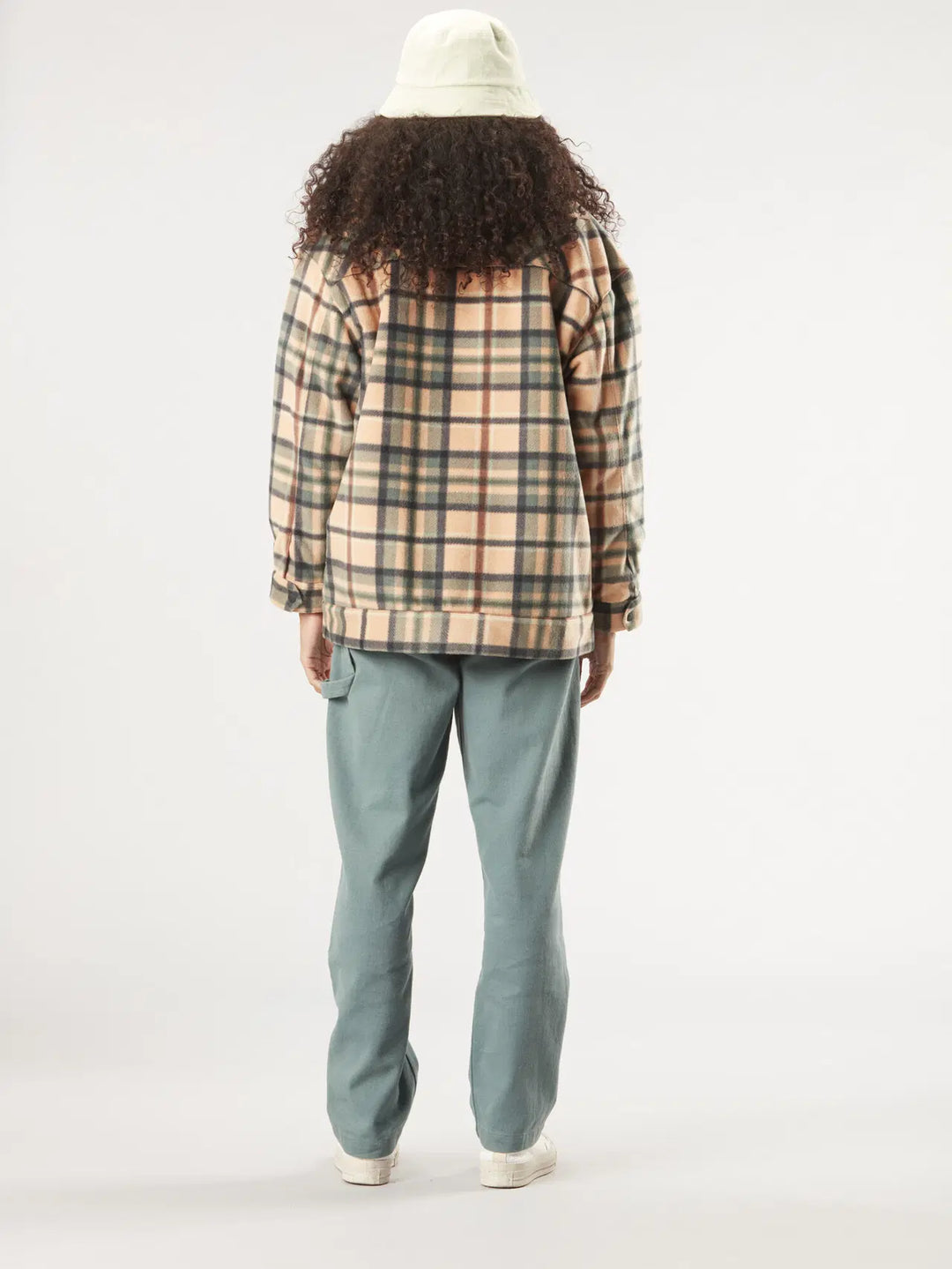 Person wearing a plaid shirt and light blue pants on a white background