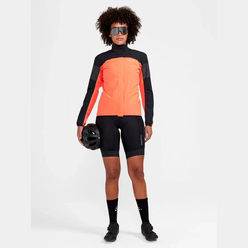 Woman wearing Craft CORE Endur Lumen Hydro Women’s Cycling Jacket in Black Shock and orange front panel, front view